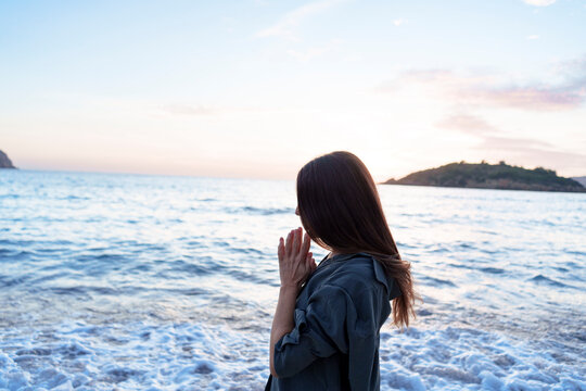 Woman with hands clasped at sunset beach