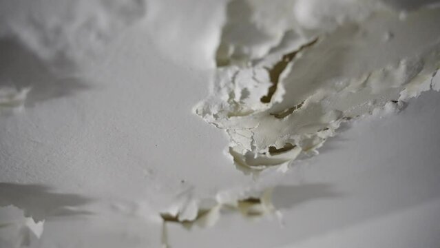White paint falling and peeling off ceiling or wall in bathroom or shower. Due to leakage of water in pipes or infrastructure in builidng paint is coming off and cracks forming due to humidity