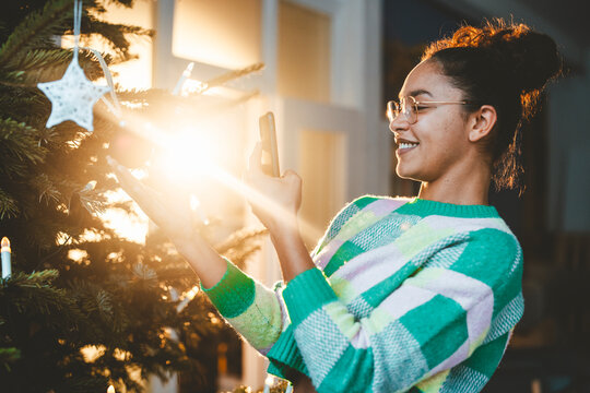 Young woman photographing Christmas tree over smart phone