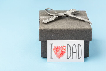 A gray gift box with a Father's Day greeting card on a blue background.
