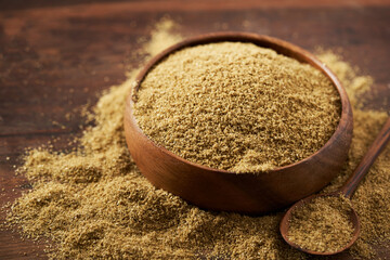 close up ground powder coriander seed in wood bowl on rustic table food background