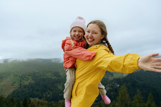 Happy mother carrying daughter on mountain
