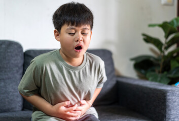 Portrait of sick unhappy little child asian boy touching belly stomach with suffering from stomach...
