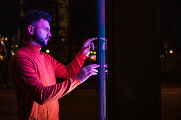 Man using touch screen kiosk at night
