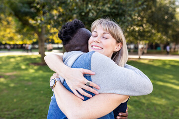 Happy multiracial friends embracing each other at park