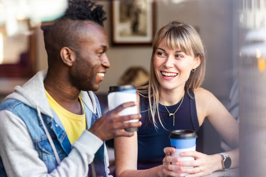 Smiling blond woman having coffee with friend at cafe