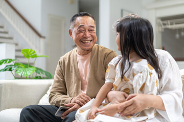 Obraz premium Portrait of happy love asian grandfather with grandmother and asian little cute girl enjoy relax at home.Young girl with their laughing grandparents smiling together.Family and togetherness