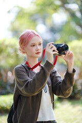 Beautiful Young artist Woman taking photo in flowers garden. Young cute girl carry the camera in the garden.