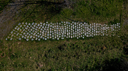 paving made of irregular flat dark gray stones overgrown with grass irregular cracked look,...