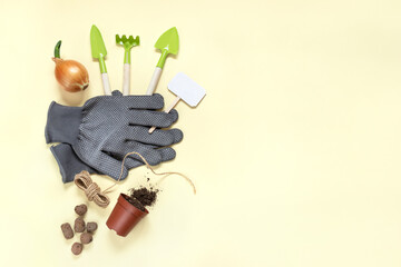 Top view of planting supplies. Gardening gloves and tools, pot for seedlings with soil and sprouted bulb on light yellow background. Preparation for horticultural season. Flat lay, space for text.