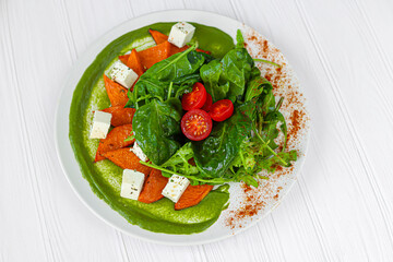 Salad of pumpkin, spinach, feta cheese and cherry tomatoes. Topped with sauce. Keto diet.