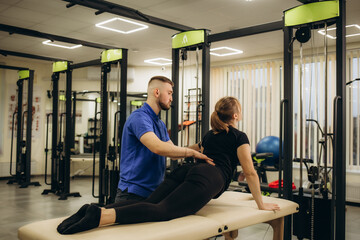 Side view of young female athlete doing back bending exercise during physiotherapy after sports...