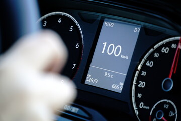 Speedometer and hands on a steering wheel - driving at 100 kmh