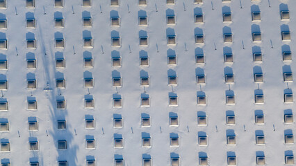 Drone photography of a large building rooftop with skylights covered by snow during winter day