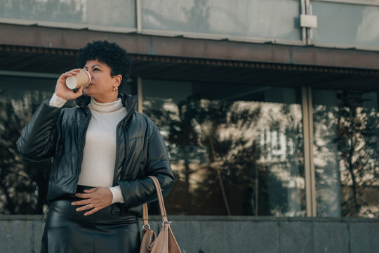 middle aged latin woman drinking coffee outdoors