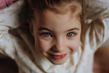 Top view portrait of little girl, charming young lady with beautiful eyes looking at the camera, smiling.