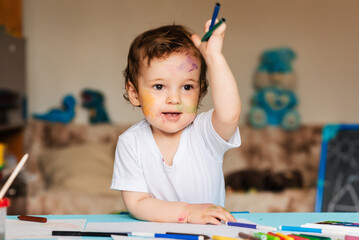 cute little boy holding colored pencils and markers