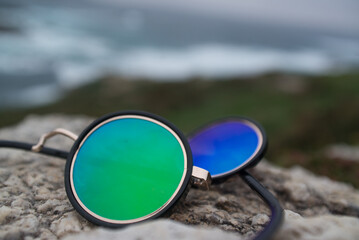 Broken glasses with blue and green reflection in the glass on the ocean shore - 761295395
