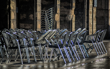 Metal chairs of a street cafe are folded after the rain. - 761295542