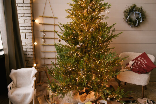 Beautiful New Year decor in a stylish interior with a Christmas tree, wreath and gifts