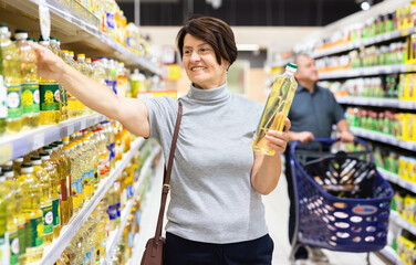 Woman chooses oil in supermarket