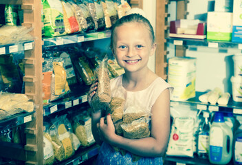 Girl holds lot of spaghetti packages in store