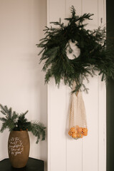 Beautiful New Year decor, a Christmas wreath made of spruce on the wall, a handmade woven string bag with tangerines