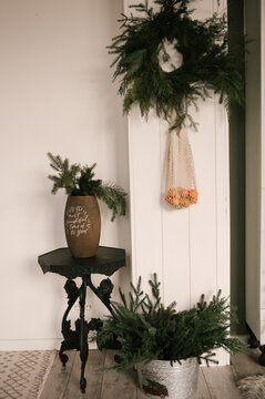 Beautiful New Year decor, a Christmas wreath made of spruce on the wall, a handmade woven string bag with tangerines