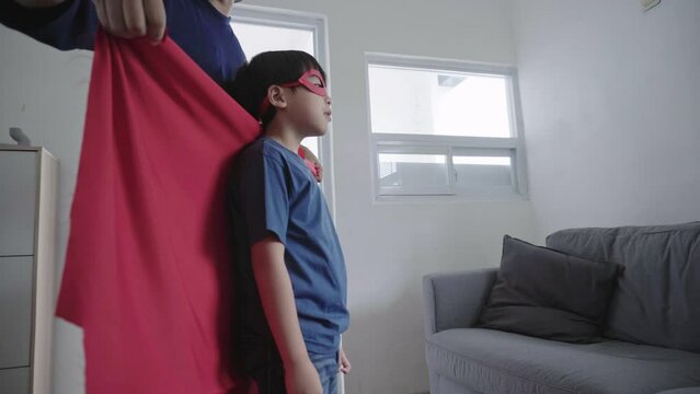 Father Dressing Son with Superhero Costume at Living Room