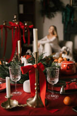 Beautiful New Year decor, a Christmas table with a red tablecloth and candles, festive dishes and glasses