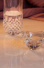 close up glass candle holder and crystal glass with reflection on marble table.  Vertical