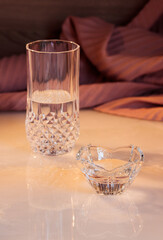 glass candle holder and crystal glass with reflection on marble table.  Vertical