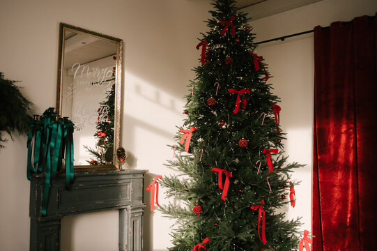 Beautiful New Year decor, the Christmas tree is decorated with red bows in the stylish interior of the living room