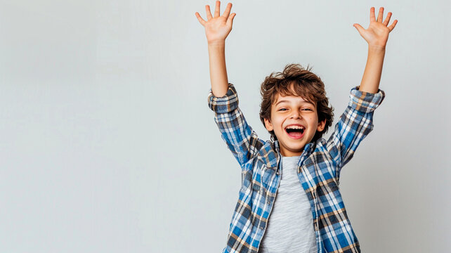 Boy in casual clothes with hands raised in joy on a white background.