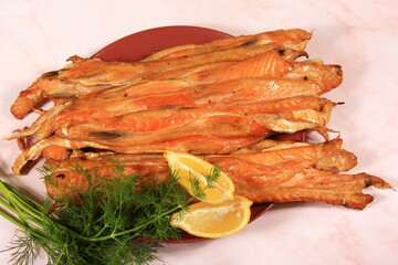 slices of smoked salmon belly on red plate, pink background. fish snack