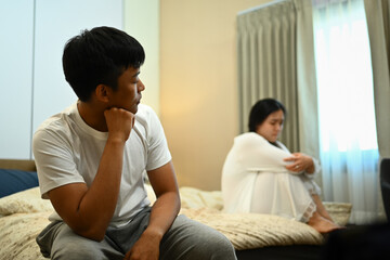 Unhappy married young couple sitting in bed, silence after conflict divorce quarrel