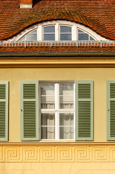 Potsdam, Germany, March 9, 2024: traditional facade with yellow plaster, red slate, white window frames and green shutters