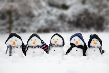 Cute little snowmen dressed in hats and scarfs in snow - 761324198