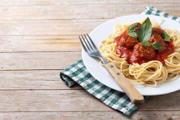 Spaghetti with meatballs on wooden table. Copy space