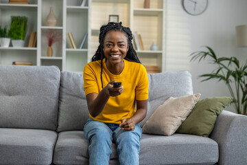 Young woman in yellow tshirt sitting on the sofa and looking excited