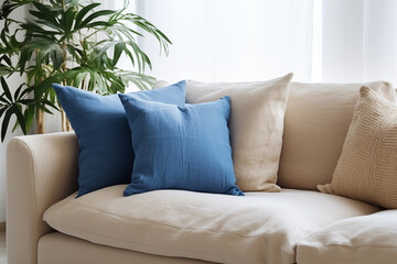 Salon avec un canapé beige et coussin bleu, zoom avec une plante