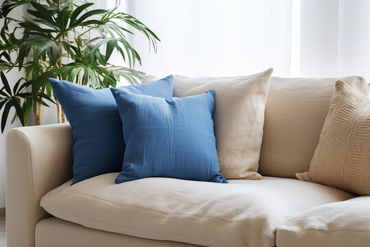 Salon avec un canap&eacute; beige et coussin bleu, zoom avec une plante