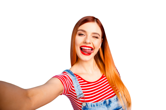 Portrait of nice vivid red cheerful straight-haired excited happy smiling young girl with opened mouth taking self picture, showing tongue out, isolated over blue background