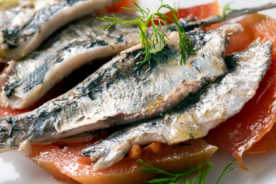 Primo piano di deliziose sardine marinate con pomodoro e cipolla, cucina italiana, cibo mediterraneo 
