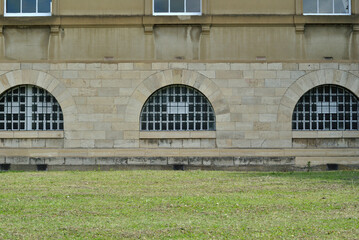 Arched Windows on Ground Floor of Old Stone Building beside Grassy Lawn