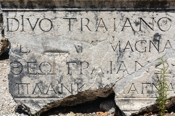 Ancient Roman Greek inscription tribute (text is name and title of 'blessed Emperor Trajan' in Latin language), Perge lapidarium, high contrast, weathered texture. Aksu, Antalya, Turkey (Turkiye)