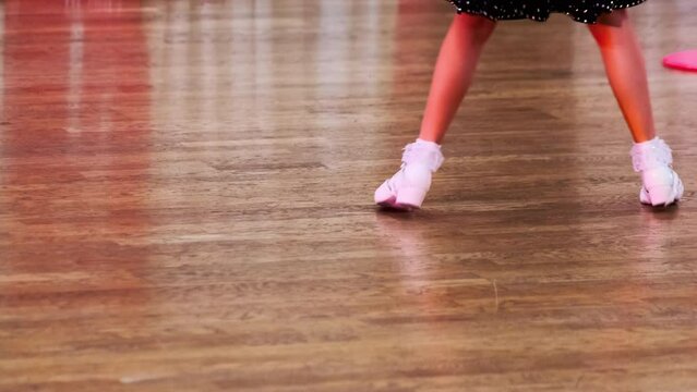 Close-up of a young child ballerina feet on wooden floor, capturing the essence of young talent and artistic dance at a competition event.