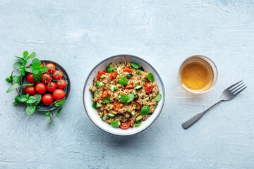 Quinoa tabbouleh salad in a bowl, a healthy dinner with tomatoes and mint, shot from the top with a drink - 761332718