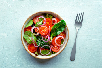 Salad with tomato, fresh leaves, and onions, overhead flat lay shot. Healthy diet, simple vegan recipe, top view - 761333391