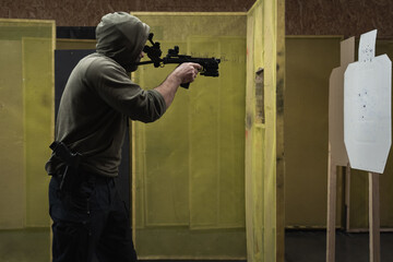 Tactical shooting from modern firearms and night vision in a shooting range. A man holds a carbine pistol in his hand.